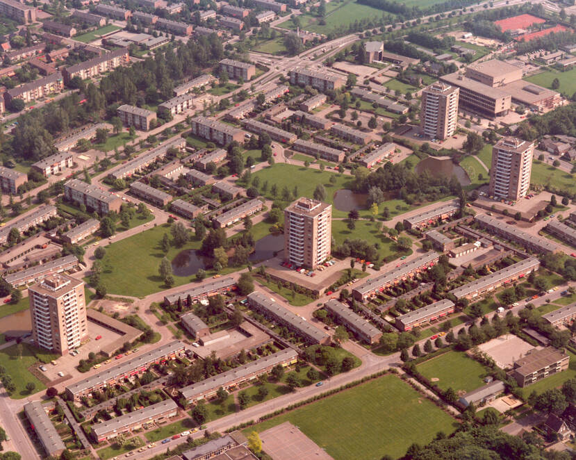 Luchtfoto van een wijk met veel groen en een flatgebouw in het  midden