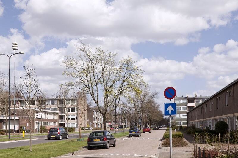 Twee parallelle wegen door een wijk waar auto's langs geparkeerd staan