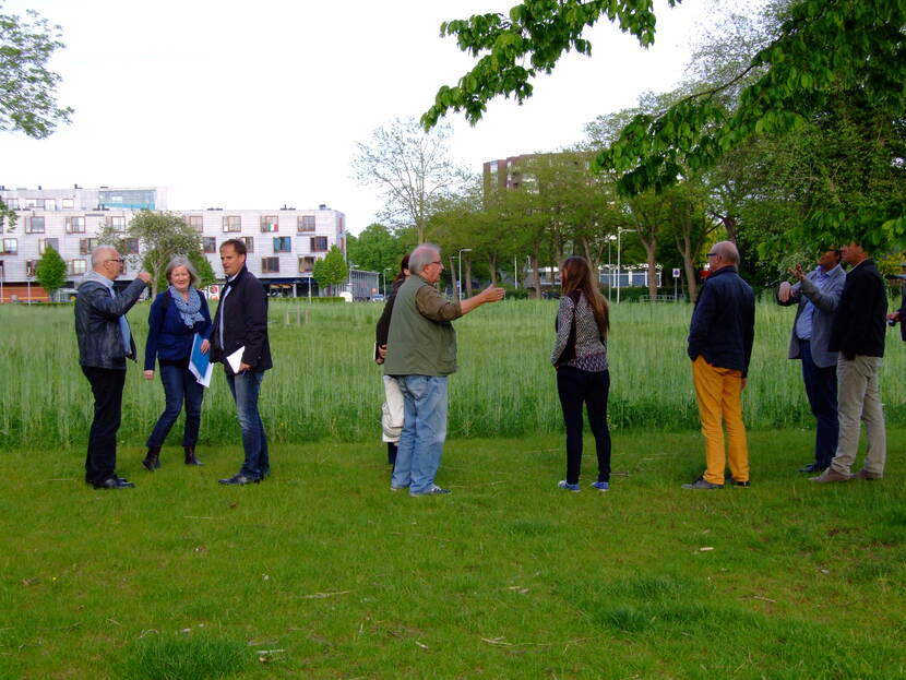 Een groep mensen staat in het gras in een wijk