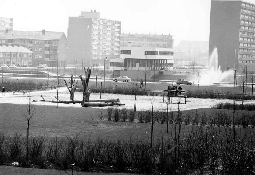 Zwart-wit foto van een vijver met een fontein in een wijk