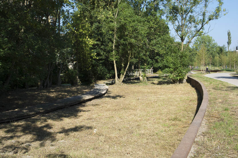 Een aangebracht hoogteverschil met de rest van het park en een cortenstalen wand die de oorspronkelijke kade markeert