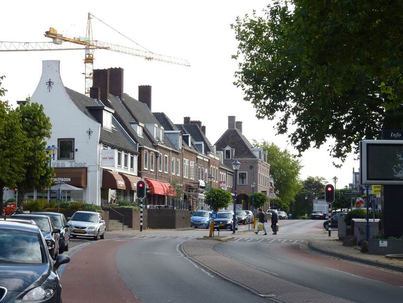 Bocht in een weg langs een wit en een aantal bakstenen huizen