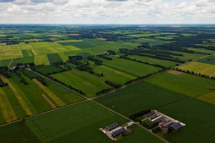 Luchtfoto met op de voorgrand grote, gelijke weilanden en op de achtergrond kleinere weilanden met verschillende afmetingen